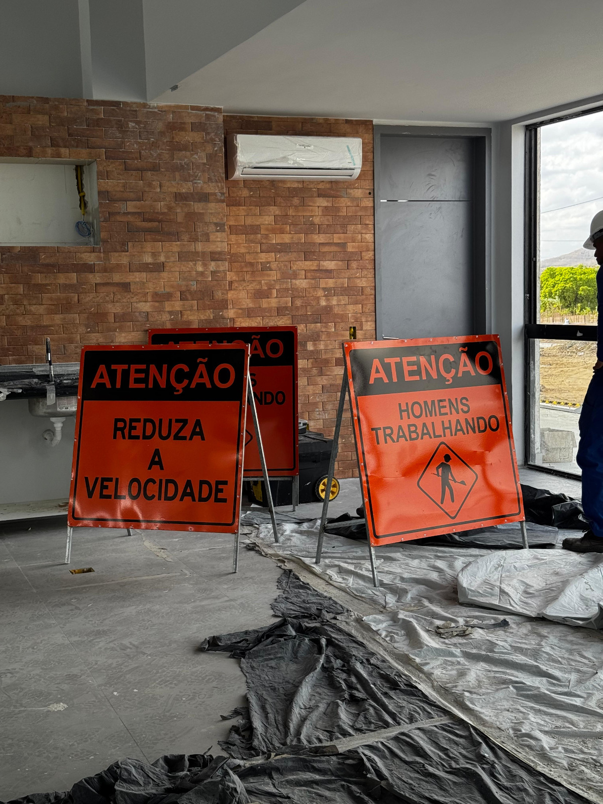 Placas 'Atenção Reduza a Velocidade' e 'Homens Trabalhando' em obra