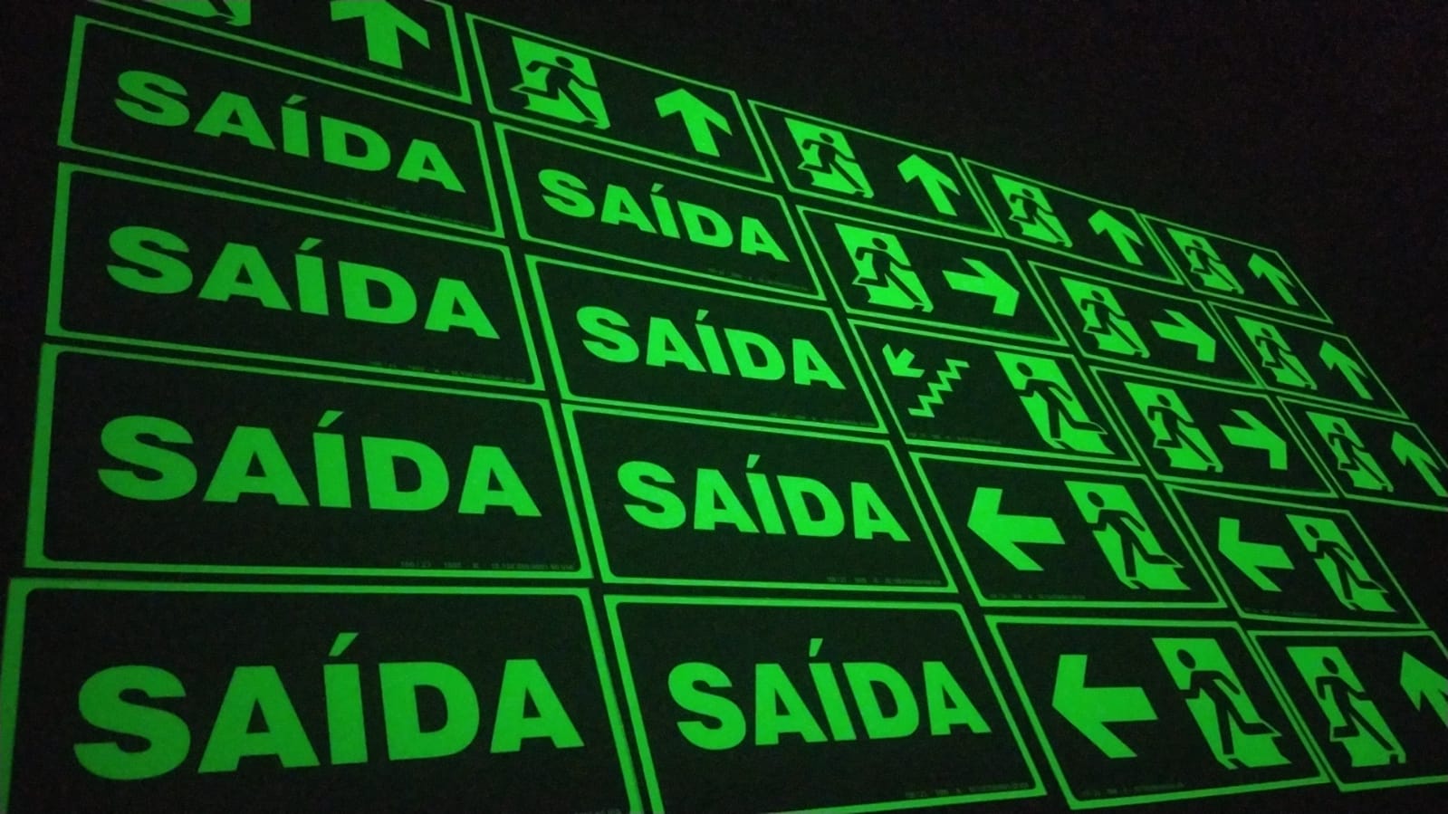 Placas fotoluminescentes de saída de emergência brilhando no escuro