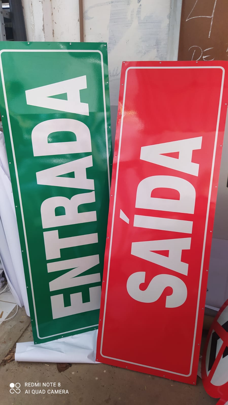 Placas de sinalização 'Entrada' e 'Saída' em verde e vermelho, outro ângulo
