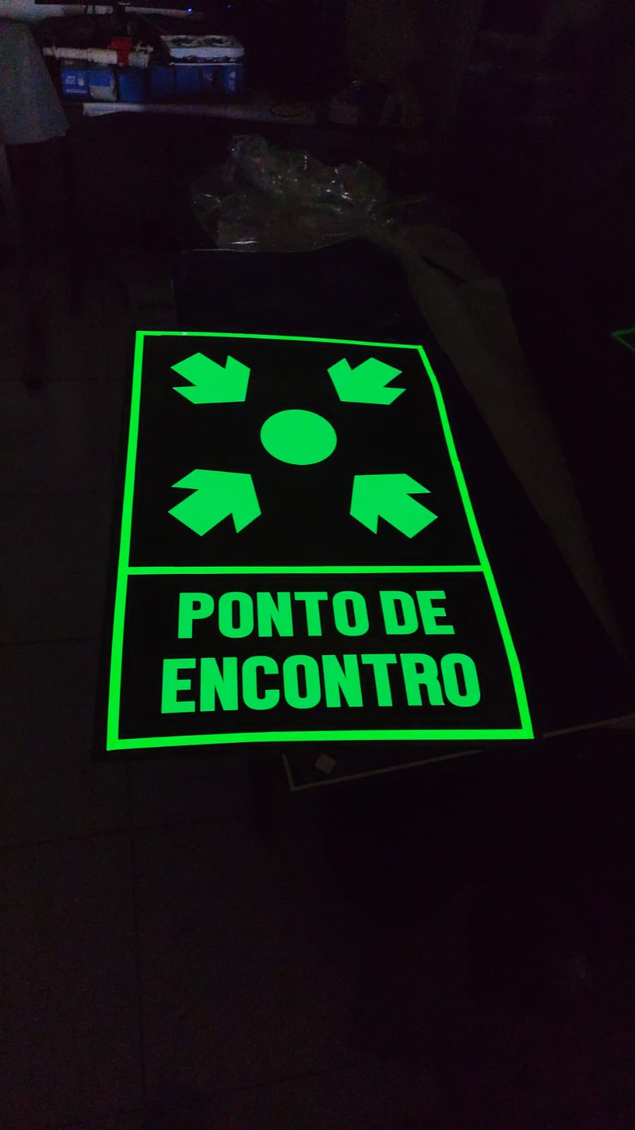 Placa fotoluminescente 'Ponto de Encontro' brilhando no escuro